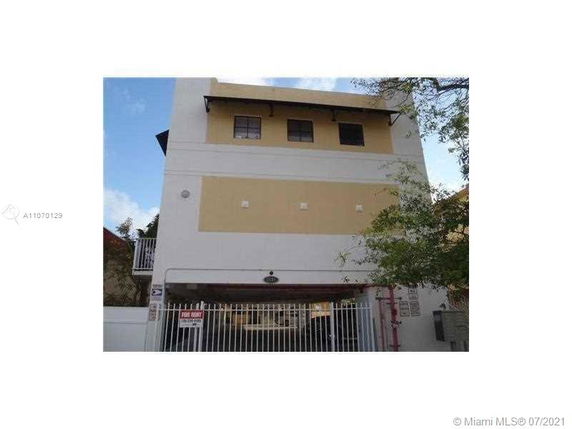 Front view of a multi-story building with a gated entrance.