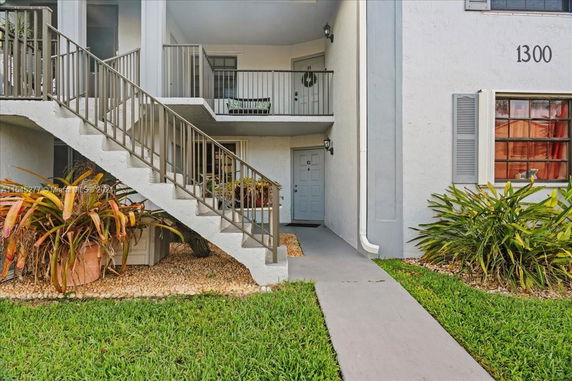 Front view of a multi-story building with stairs leading to an upper-level entrance.