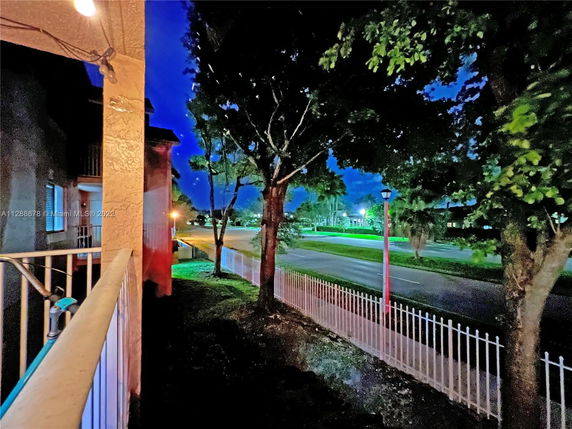 View of a street with trees and a sidewalk at night from a building.