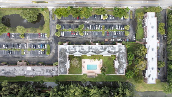 Aerial view of a building complex with a central swimming pool and parking lots.