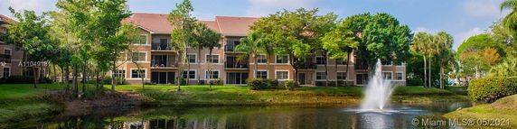 Three-story residential building with balconies and a pond with a fountain in the foreground.