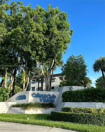 Front view of a multi-story building named Calusa Club Village.