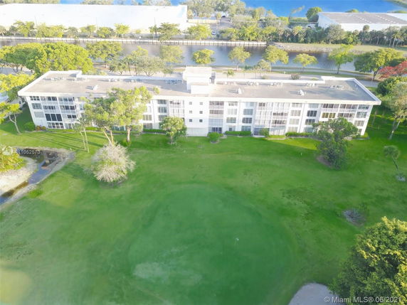 Aerial view of a large multi-story building surrounded by greenery and a waterway.