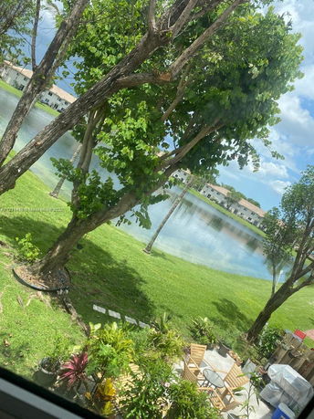 View of a lake and surrounding houses with trees and a patio area.