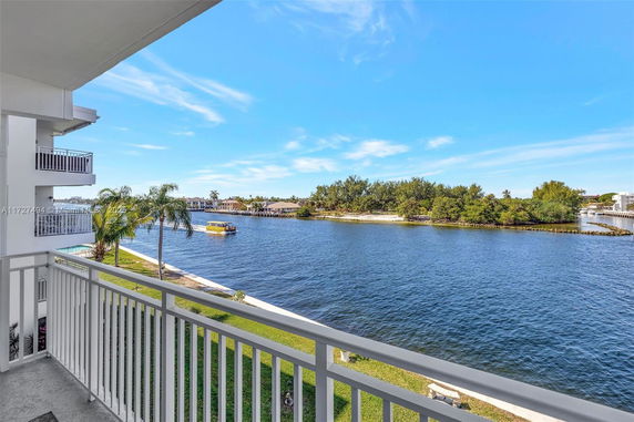 Waterfront view from a balcony overlooking a waterway with a boat and nearby shoreline.
