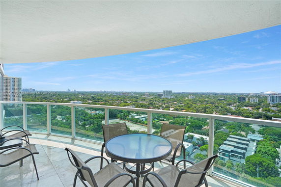 Wide-angle view from a building balcony showing a cityscape and greenery.