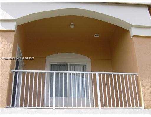View of a balcony with white railing and beige walls.