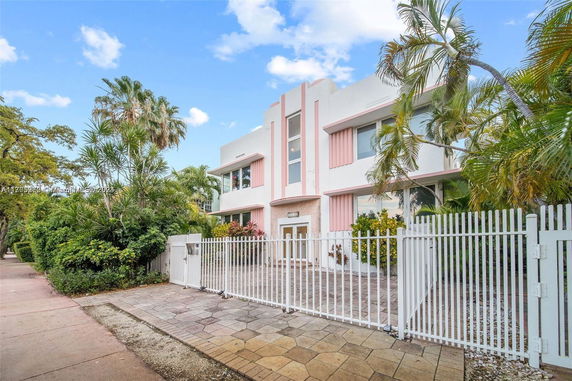 Front view of a two-story house with pink accents and surrounding greenery.