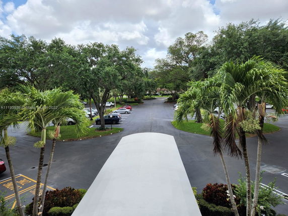View of a parking area with cars and surrounding trees.