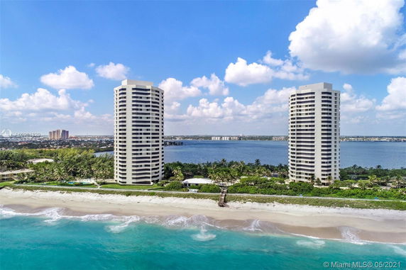 Front view of two tall residential towers near the beach.