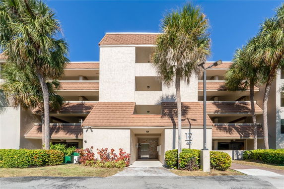 Front view of a multi-story building with balconies and a tiled roof.