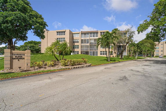 Front view of a multi-story residential building with beige facade and large windows.