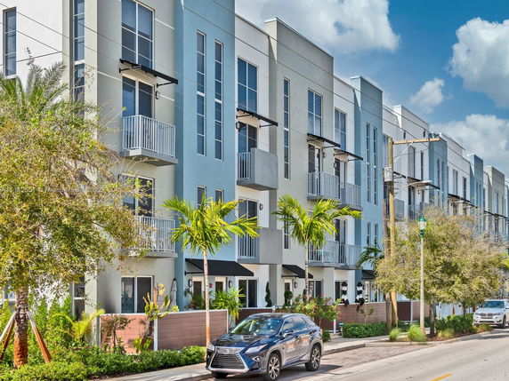 Front view of a modern multi-story row house building with balconies.