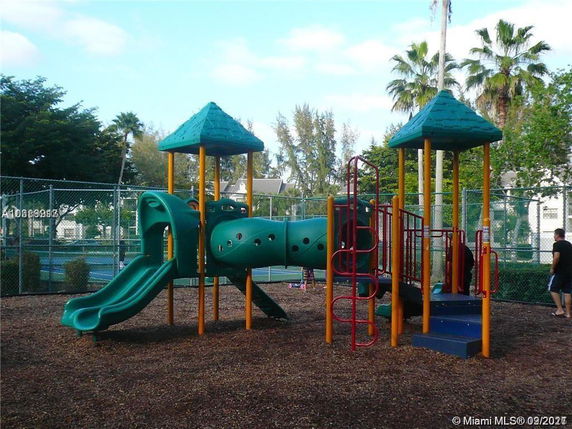 Playground with slides and climbing structures surrounded by fence.