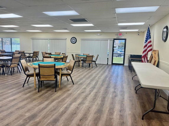 Indoor common area with round tables and chairs, resembling a recreation or meeting space.
