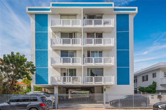 Front view of a multi-story building with balconies and blue panel accents.