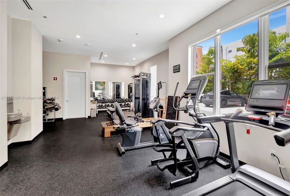 Interior view of a gym with exercise equipment and windows.