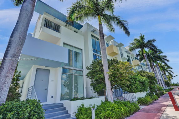 Front view of a modern multi-story building with balconies and large windows.
