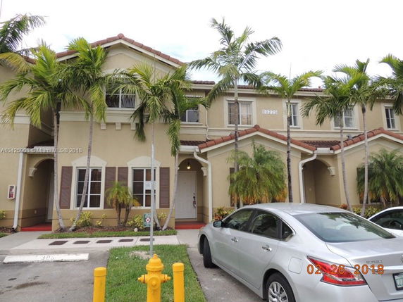 Front view of a two-story house with a tiled roof and a driveway.