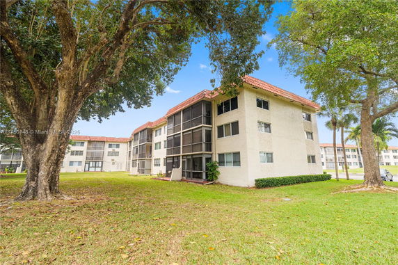 Front view of a multi-story residential building with screened balconies and red-tiled roof.