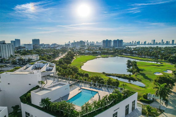 Panoramic view of a cityscape with buildings, a golf course, and a rooftop pool.