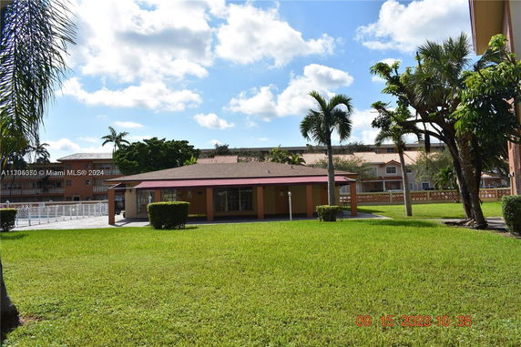 Front view of a single-story building with a red roof and surrounding grass area.