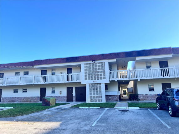 Front view of a two-story residential building with a white exterior and balcony railing.