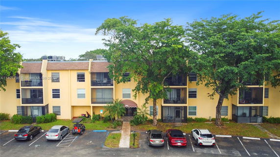Front view of a multi-story apartment building with a brown roof and balconies.