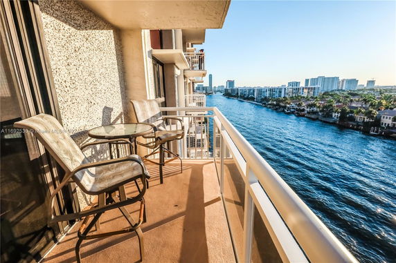 Balcony overlooking a body of water and distant buildings.