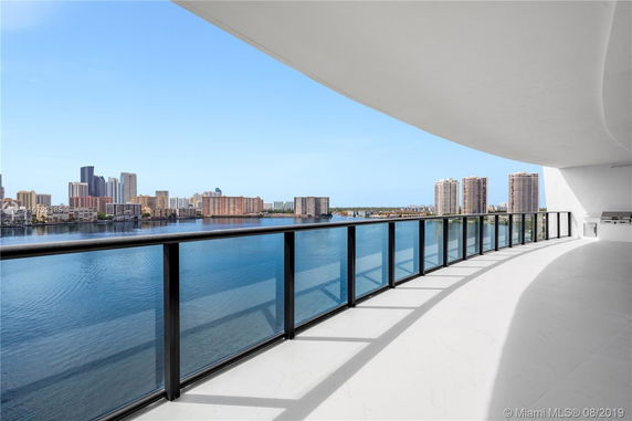 Panoramic view of a cityscape with high-rise buildings and waterfront from a large balcony.