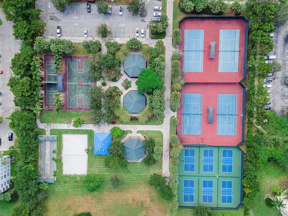 Aerial view of outdoor sports complex with tennis courts and a basketball court.