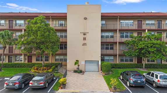 Front view of a multi-story building with balconies and a paved entrance.