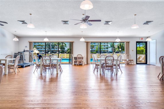 Interior view of a recreational area with tables, chairs, and exercise equipment.