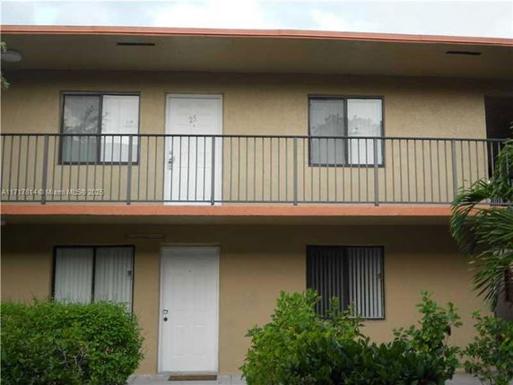 Front view of a two-story building with balconies and multiple windows.