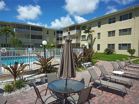 Outdoor view of a residential building with a swimming pool and lounge chairs.