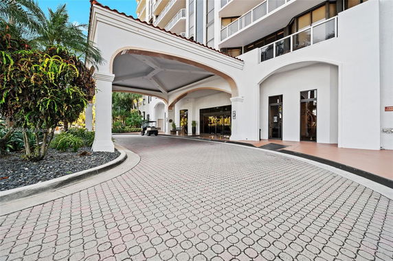 Front view of a multi-story building with an arched entrance and driveway.