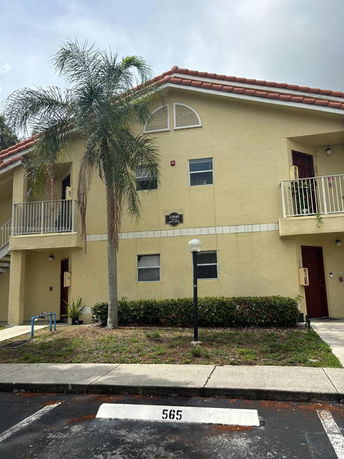 Front view of a two-story residential building with a red-tiled roof and balconies.