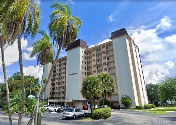 Front view of a multi-story apartment building labeled 'Briarwood' with balconies and a parking area.