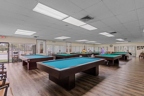 Room with multiple billiard tables and seating areas.