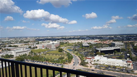 Panoramic view of a cityscape with buildings, roads, and parking areas.