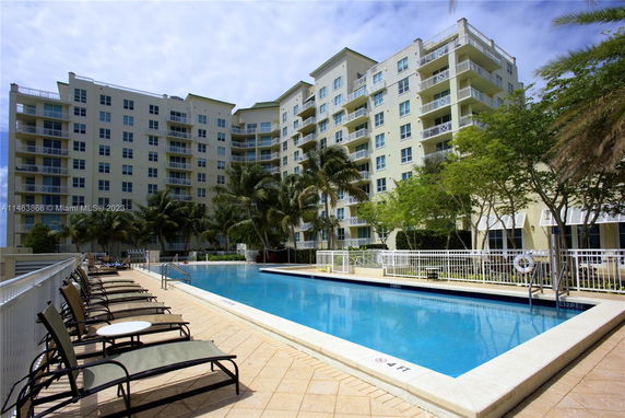Outdoor swimming pool with a multi-story residential building in the background.