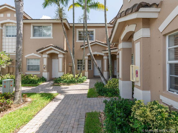 Front view of a two-story townhouse with beige exterior and white trim.