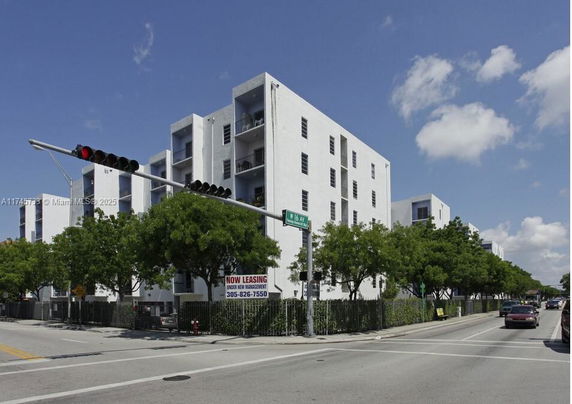 Front view of a multi-story apartment building with a modern design and surrounding trees.