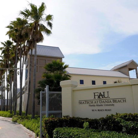 Front view of a university building with palm trees.