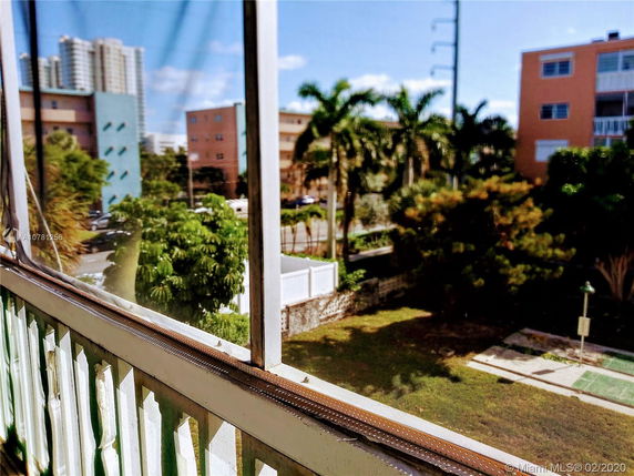 View from a balcony showing nearby buildings and trees.