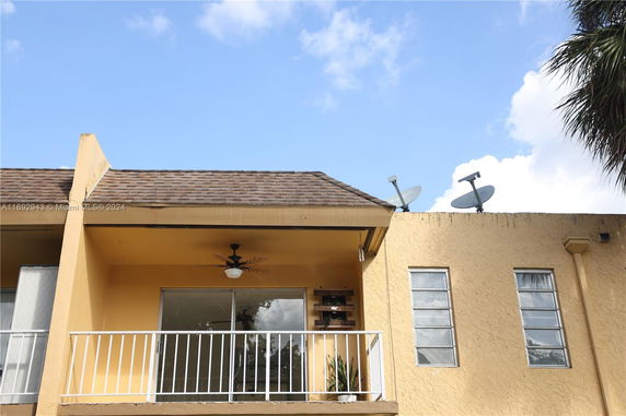 Front view of a building with a balcony and satellite dishes on the roof.