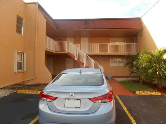 Outdoor parking area with a car parked in front of a two-story building.
