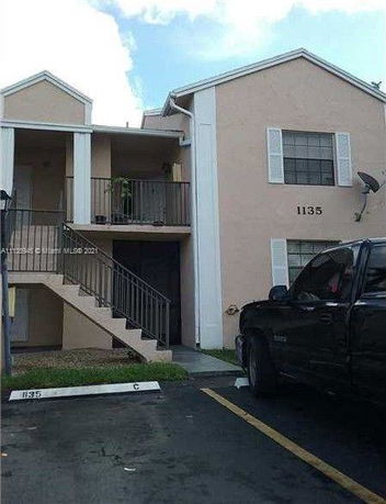 Front view of a two-story residential building with an external staircase and balcony.