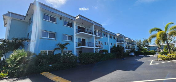 Front view of a multi-story blue residential building with balconies.