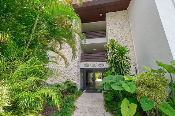 Entrance of a building with stone walls and greenery on either side.